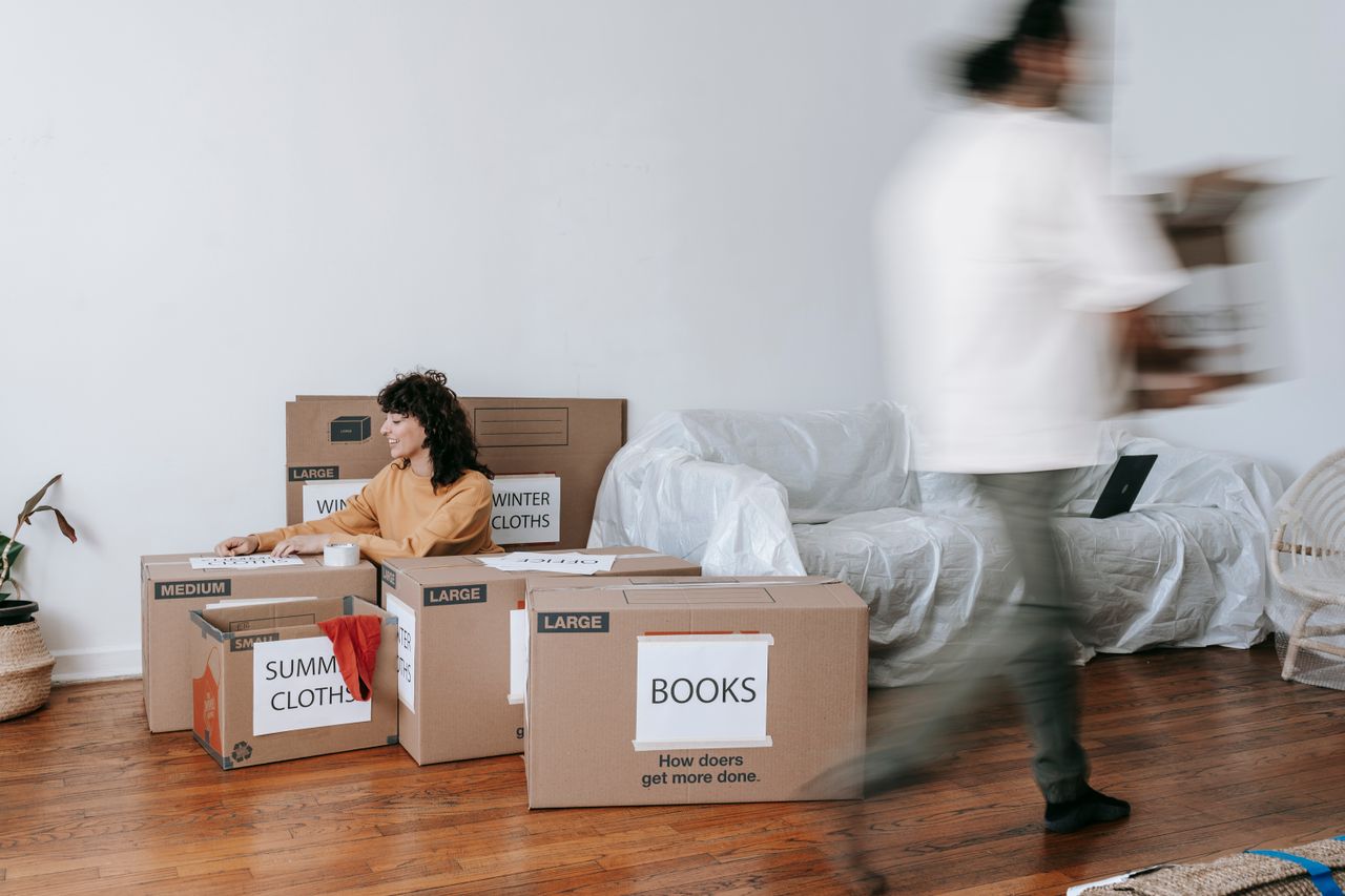 our-mission A couple arranging labeled boxes in a minimalist living room while getting ready for moving day.