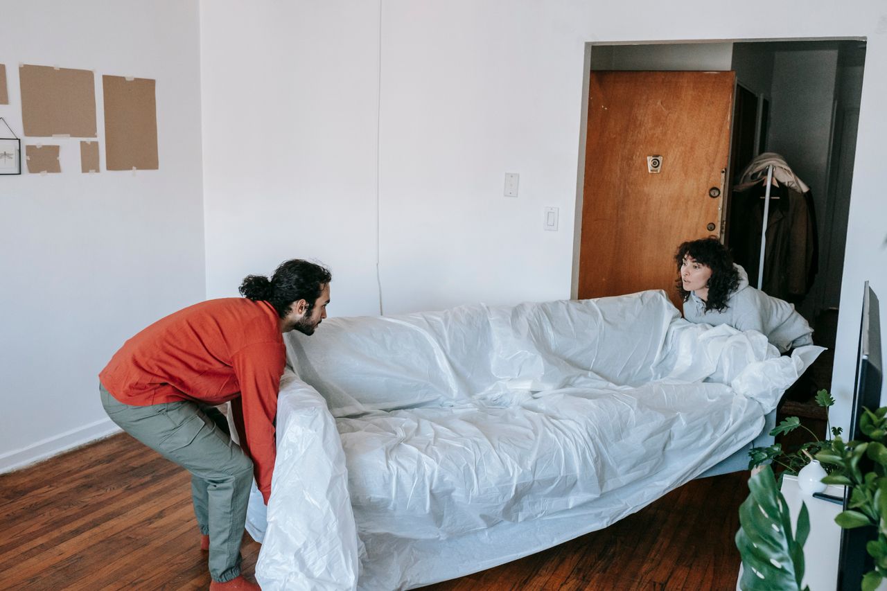 Un couple porte ensemble un canapé en emménageant dans un nouvel appartement.